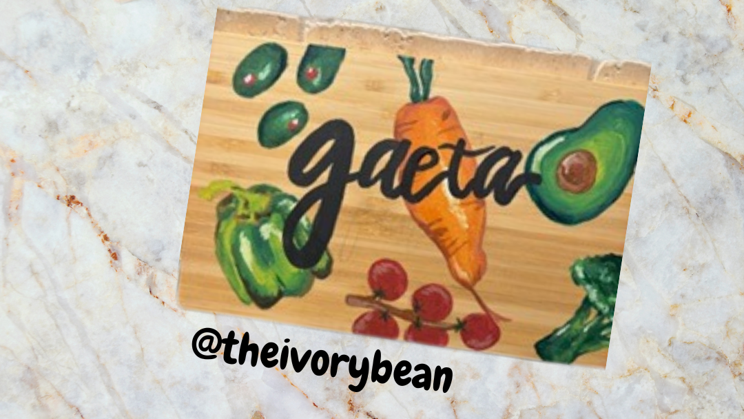 Two wooden cutting boards with vegetable illustrations and 'gaeta' text on a marble surface, branded '@theivorybean'.